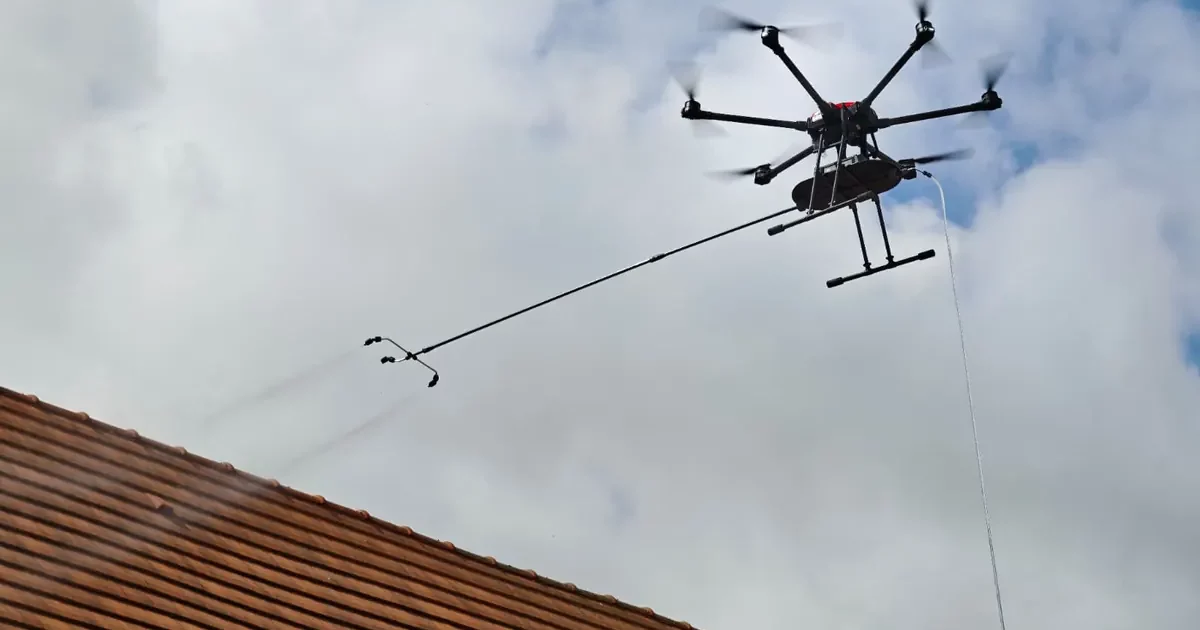 Drone de pulvérisation en vol au-dessus d'une toiture pendant la formation démoussage par drone TELEPILOTE à Marcq