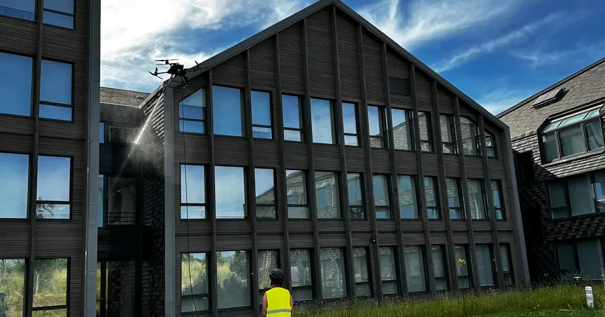 Drone de nettoyage devant la façade vitrée d'un immeuble de bureaux